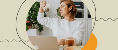 Woman handling money while sitting indoors next to a computer.